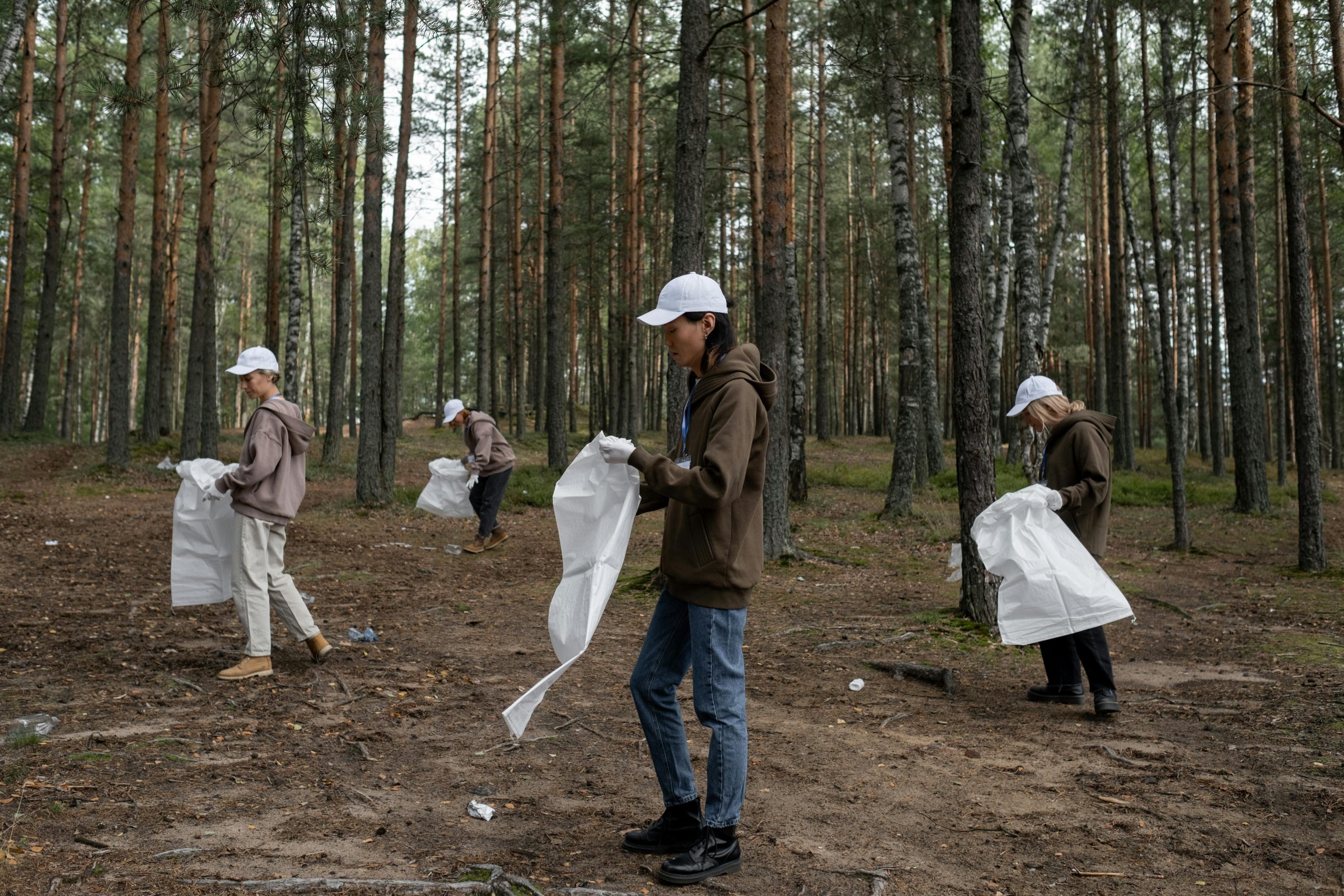 Group of volunteers cleaning up litter in a forest, promoting environmental conservation and community effort.